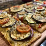Close-up view of a roasted vegetable flatbread with vibrant toppings.