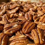 Close-up view of toasted pecans on a wooden surface.