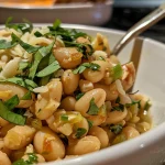 Close-up of cheesy chile crisp white beans in a bowl.