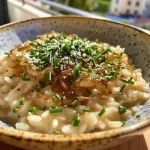 Creamy vegan risotto topped with caramelized onions and scattered chives.