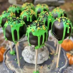 Close-up of colorful Witches Cauldron Cake Pops with green frosting and candy melts.